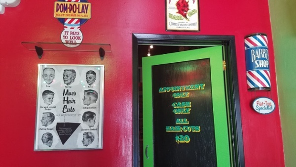 Mac's appointment-only barber shop door surrounded by vintage signs