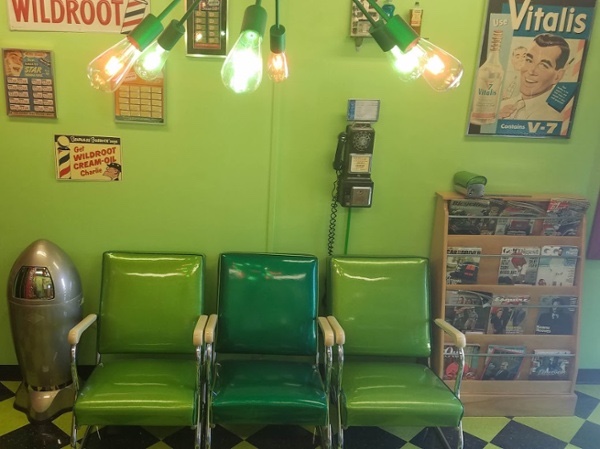 Green vintage waiting chairs beneath barber shop lights and memorabilia